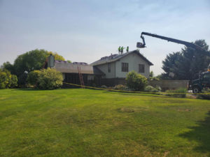 Crane loading new tiles on top of a house undergoing a reroofing project in Twin Falls, ID.