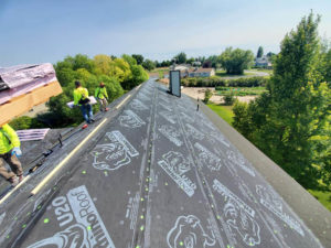 View from on top of a house with tradesmen loading tiles onto the roof during a reroofing project in Twin Falls, ID.