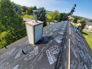 Professionals loading new tiles onto a roof of a house undergoing a reroofing project in Twin Falls, ID.
